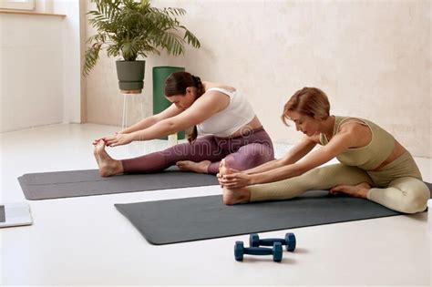 Concentrated Women Stretching Legs Couple Woman Sitting On Yoga Mat