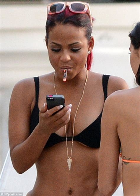 christina milian risks spilling out of her too small bikini as she puffs on e cigarette at the