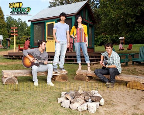 men   woman  playing guitars  front   small cabin  logs