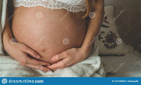 attractive pregnant woman is sitting in bed and holding her belly last