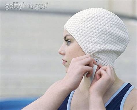 A Woman Wearing A White Knitted Hat While Holding Her Hand To Her Ear
