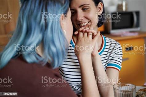 Happy Lesbian Couple Holding Hands And Sitting In The Kitchen Stock