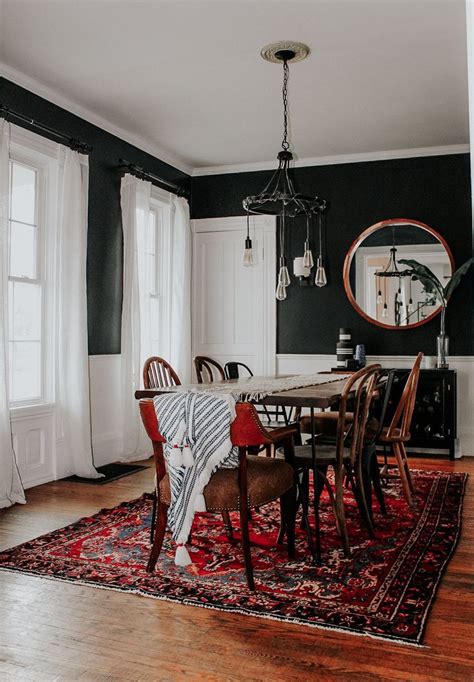 moody eclectic dining room  black walls mismatched wood chairs