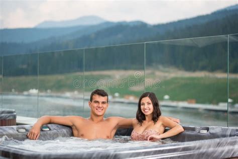 Young Couple Relaxing Enjoying Jacuzzi Hot Tub Bubble Bath Outdoors On