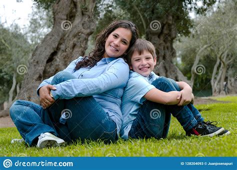 mom and son sitting on green grass in green park concept of happy