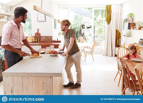 same sex male couple with daughter making breakfast at home together
