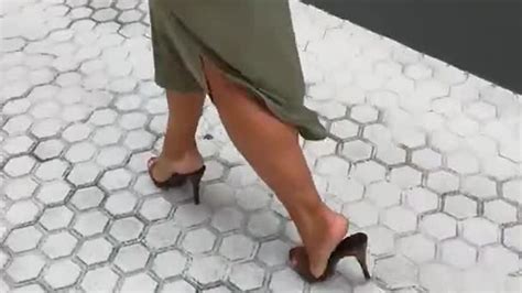 woman with attractive legs and perfect feet walking down town in sexy mules