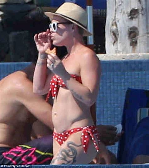 pink shows off her sculpted figure in a polka dot bikini while tucking into pizza on holiday