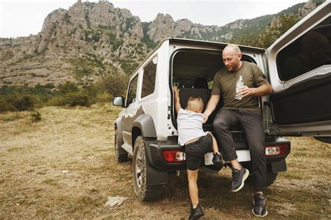 heureux père et fils assis dans le coffre de la voiture photo premium