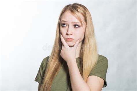 Embarrassed Unsure Young Woman Holds Her Chin And Purses His Lips