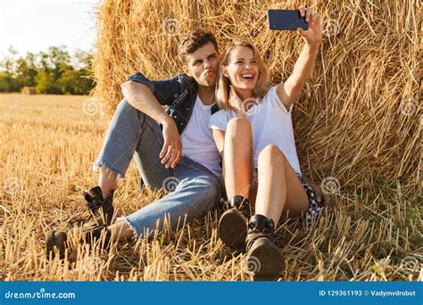 Photo Of Modern Couple Man And Woman Taking Selfie While Sitting Stock