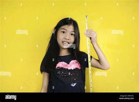 A Cute Young Asian Girl Is Playing With A Yellow Measuring Tape