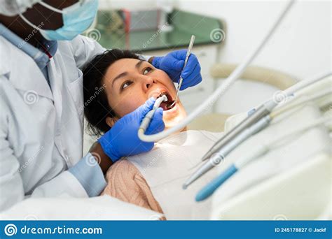 Woman Receiving Professional Teeth Treatment In Dental Office Stock
