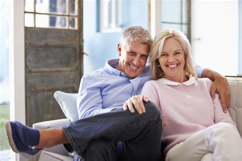 Portrait Of Smiling Mature Couple Sitting On Sofa At Home – The Global