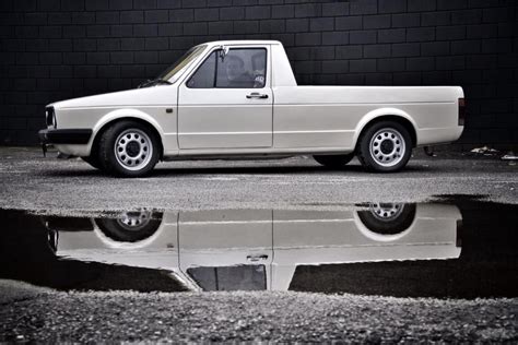 white car parked  front   brick wall    puddle   ground
