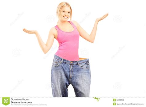 gelukkig gewichtloos wijfje met oud paar jeans die met hij gesturing stock afbeelding image