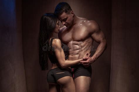romantic bodybuilding couple against wooden wall stock