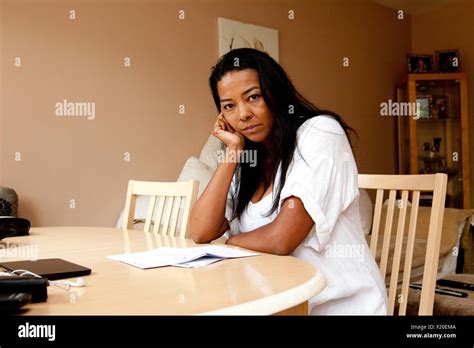 portrait of fed up mature woman sitting at dining table reading bill