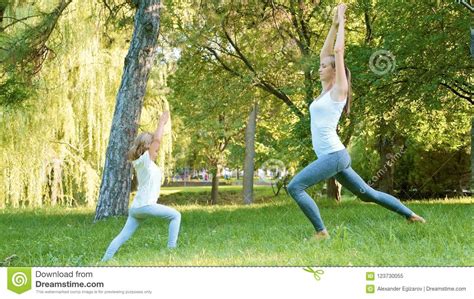 mother and her little cute daughter doing yoga exercise together stock