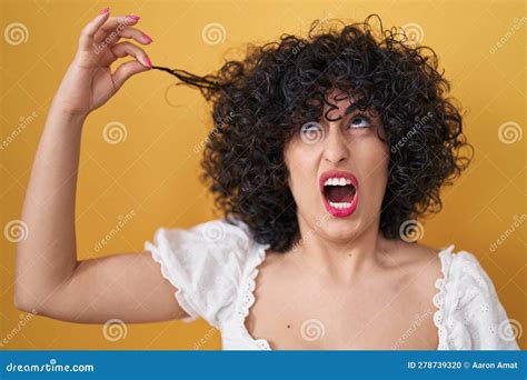 Young Brunette Woman With Curly Hair Holding Curl Angry And Mad