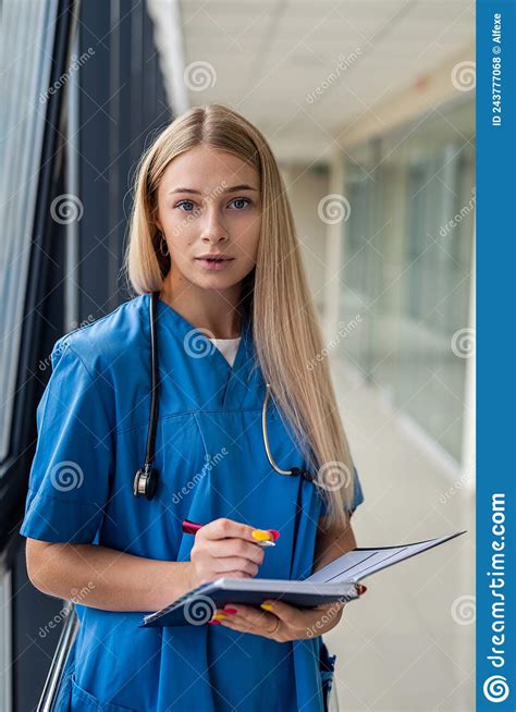 Beautiful Blonde Nurse Holding A Notebook With A Pen In The Hospital