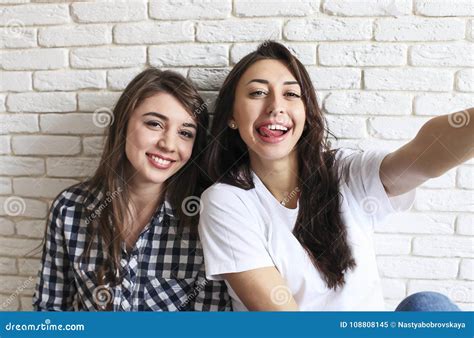 Portrait Of Two Millennial Females Fooling Around In Front Of Mobile
