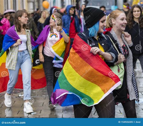 Young Lesbian Couple With A Rainbow Flag Attending The Gay Pride Parade