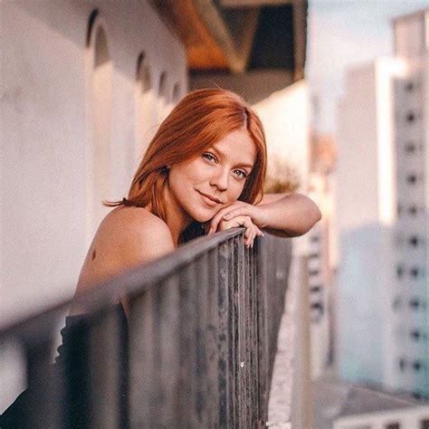 A Woman With Red Hair Leaning On A Balcony Railing Looking At The