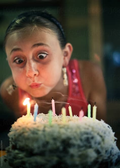 «girl With Wide Eyes And Puffy Cheeks Blowing Out Birthday Candles On A