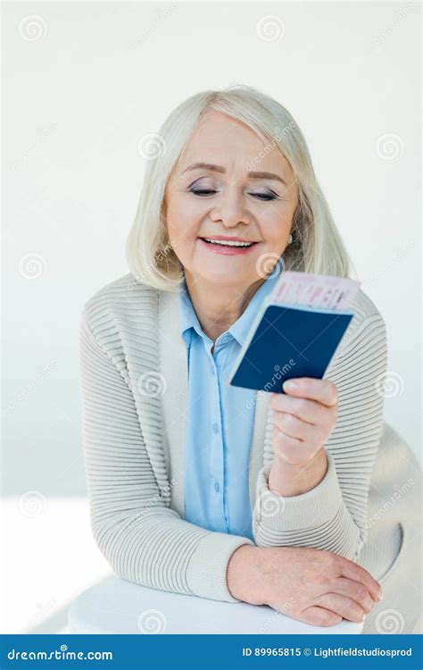 portrait of smiling senior woman looking at passports and tickets stock