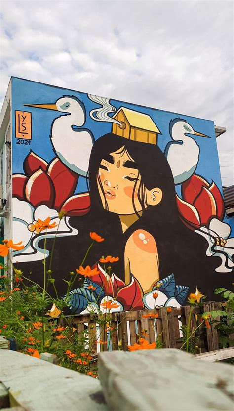 A Mural On The Side Of A Building With Flowers In Front Of It And A