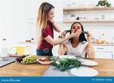 girls fooling around in the kitchen playing with vegetables stock