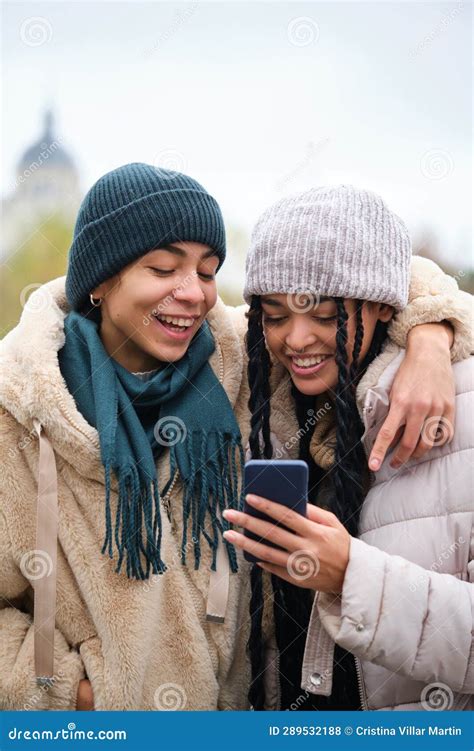 Happy Dominican Lesbian Couple Using The Phone At Street In Winter
