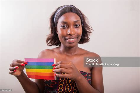 an african lesbian girl is holding a rainbow flag and smiling in the