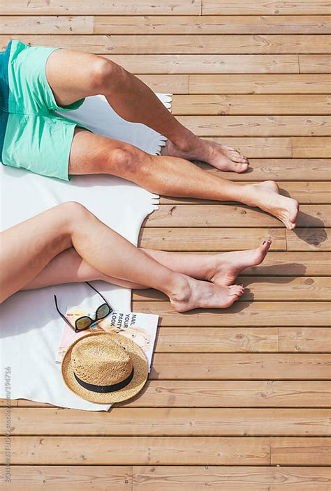 cropped view of beautiful couple sunbathing on a wooden terrace summer