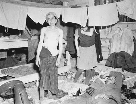 emaciated female survivors stand beneath hanging laundry in the newly