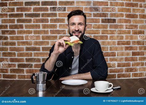 Handsome Bearded Young Man Eating Sandwich And Drinking Coffee Stock