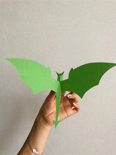 hand holding   green paper bat   shaped   dragons wings