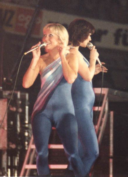 two women standing on stage with microphones in their hands and one
