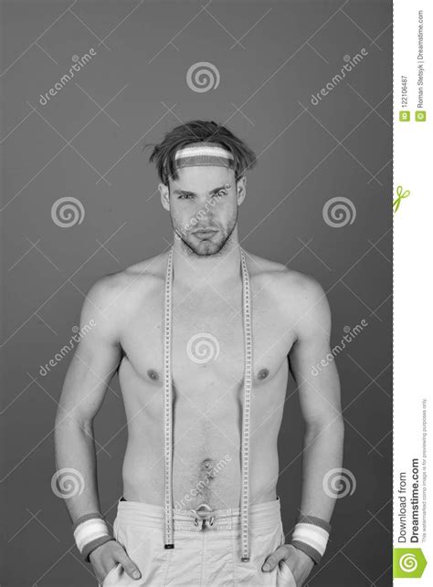 man with naked torso and yellow measure tape on neck on purple
