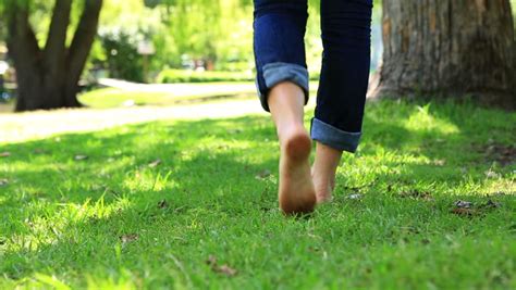 woman walking barefoot on the grass on a sunny day stock footage video