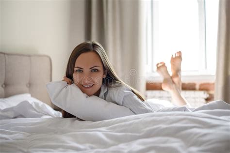 portrait of smiling woman in bed lying on her stomach stock image