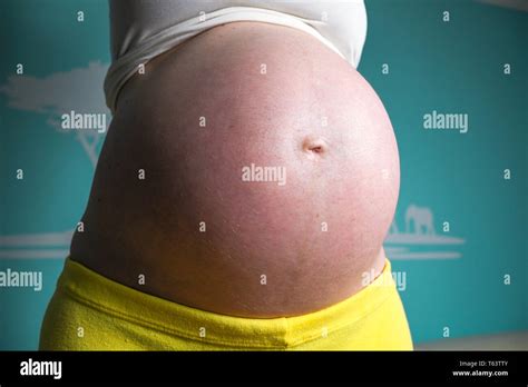 Young Pregnant Girl Showing Her Big And Nicely Rounded Belly At Home