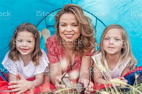 portrait of cute blonde mom with her daughters lying down in a blue