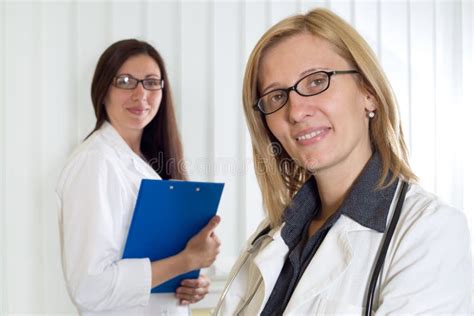 Portrait Two Smiling Confident Female Doctors Looking Camera Over White