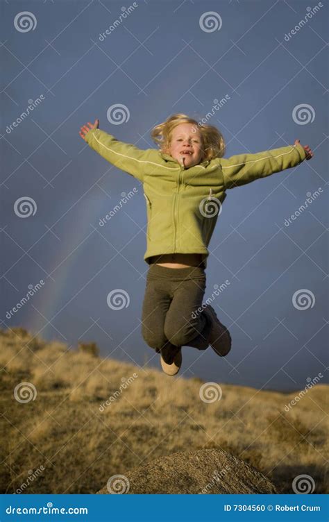 girl jumping beneath  rainbow stock photo image  peaceful scenery