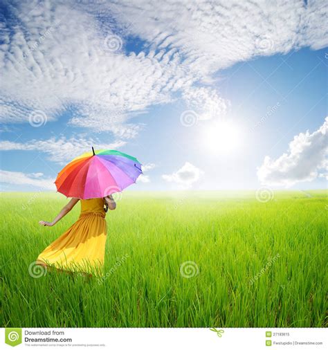 beautiful woman holding umbrella in green grass field and