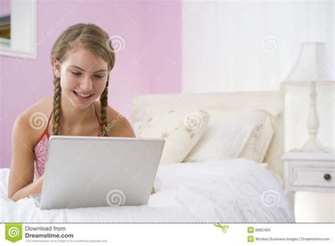 teenage girl lying on bed using laptop royalty free stock