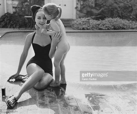 model seated by pool edge wearing a black one piece bathing suit news photo getty images