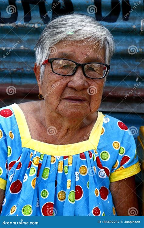 a mature filipino woman rests on a sidewalk and poses for the camera